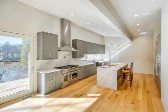A 20-foot, Passive-house-rated sliding glass door provides a panoramic view of the river from the main living space. The steel beam that supports the gently sloping butterfly roof is exposed in the open floor plan. 