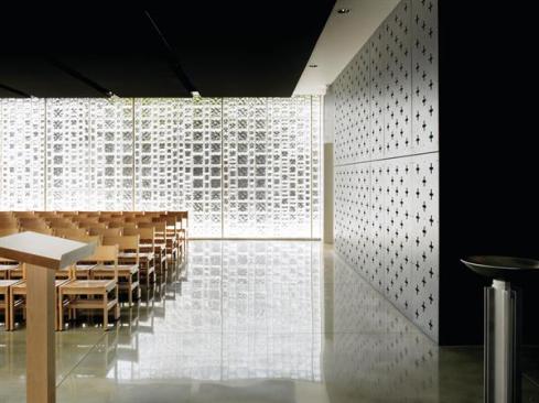 In contrast to its three glass walls, the chapel's fourth wall is clad in cement panels with nearly 4-inch-square, cross-shaped perforations. Natural light filters in and reflects off of the polished concrete floors.
