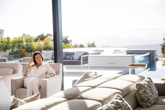 Modern resort style living room with glass walls that open up to outdoor poolside living.