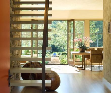 Outside the dining room, an alley of hawthorn trees culminates in a blue urn.