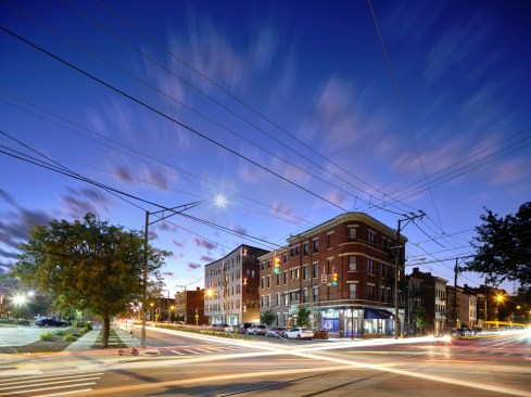 Willkommen on Pleasant’s elegantly creased brick bulk rises above a large, glass storefront, inviting activity across Liberty Street. 