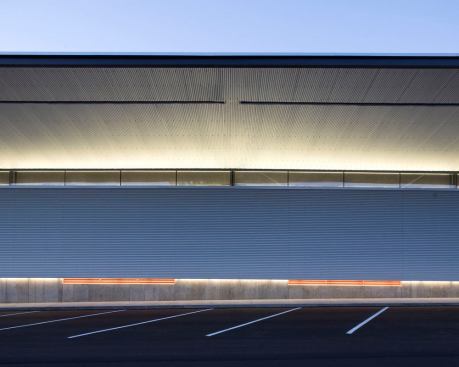 Fluorescent light strips fully integrated into the skin of the structure uplight the soffit and downlight the entry sidewalk.