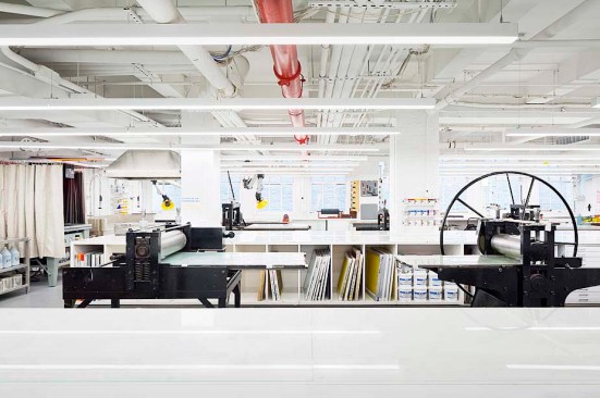 Dry making zone: printmaking, lithography and silkscreen slip in below a tangle of existing building services. A newly restored light well beyond offers daylight and an expanded sense of space at the cellar level.