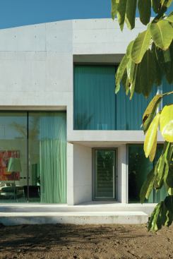 The white concrete walls of the house contrast against the saturated jewel tones of the Mediterranean sky.