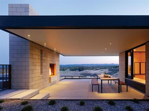 A covered terrace with a fireplace links the home's public wing with the pool area, facilitating outdoor dining throughout the year.