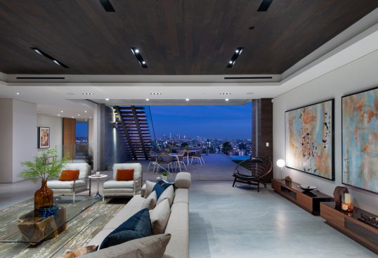 Luxury open plan dining room, bar and living room with views through sliding glass walls.