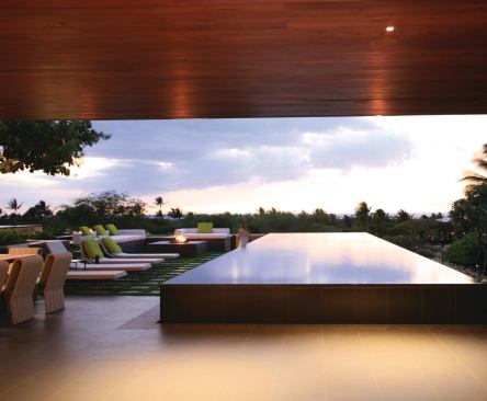 The living room continues out to the lanai, where a dark lava-rock pool reflects light and Hawaiian sunsets.