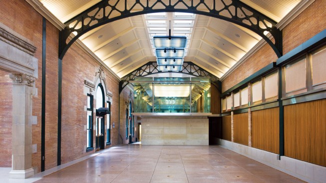 Inserted at the north end of the Schi. Family Great Hall (left) and in front of the main entry doors (opposite middle left) is a discrete volume with restrooms below and a glass-enclosed meeting room above. The base of the mezzanine is clad in large panels of limestone and detailed with bands of stainless steel. The upper-level room, which is equipped with darkening shades, can be used for breakout sessions, small luncheons, or as a bride's dressing room.