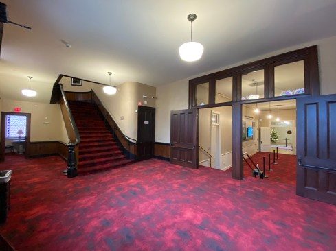 Accessed by three monumental stairs, the restored front lobby of the building seen here is three feet above most of the first floor seen at the right and six feet above grade at the front of the building. The new elevator bypasses the multiple levels at the front entry and connects the basement, ground floor, Great Hall, and balcony levels.
