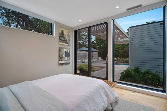 The guest bed looks out past the pool deck and pool to the dunes.
