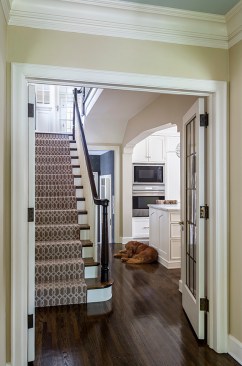 French doors in hallway open to view of stairs and kitchen entrance with dog lying on floor