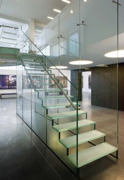A meticulously detailed glass stair connects the gallery to second-floor offices.
