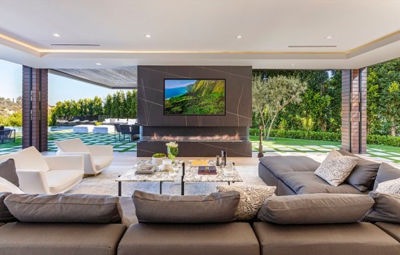 Resort style indoor outdoor living room with sliding glass walls at Los Angeles modern home.