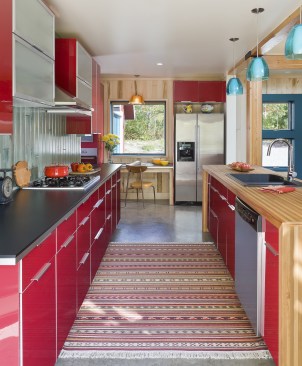 View between cabinets and island in kitchen with shiny red cabinets 