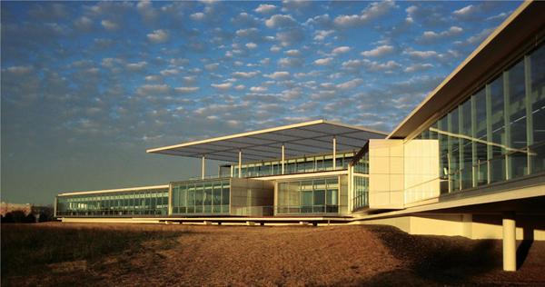 The building's S shape and ample glazing mean that not only do employees get views of the wetlands, they can also see into other parts of the workspace, creating a visual sense of community throughout the long, thin building. At the center of the structure, a roof deck?connected to a second-story employee lunch room?is covered with a metal-grate awning that provides some shading and contributes to the building's horizontal aesthetic.