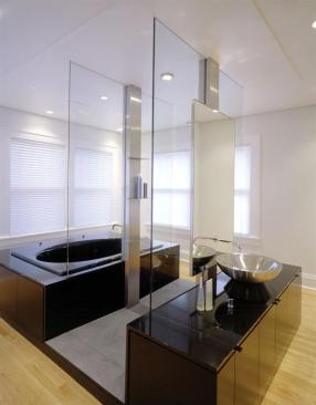 The molding, trim, and wood floors in the bath match the Craftsman look found throughout the home, while sleek materials, such as highly polished black granite, glass, brushed stainless steel, and slate, make the tub/shower/sink combo contrastingly contem