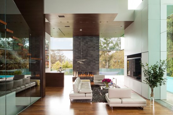 Luxury Beverly Hills home family room with stacked slate fireplace and double height glass walls.