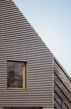Façade detail showing a frameless, exterior flush window on the second floor.