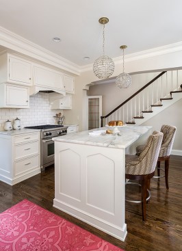 Stairway descends behind white kitchen and kitchen island