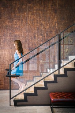 A grand open stairway, which rises from the entrance lobby to the second floor amenities space, is lined with a natural, wood bark wall covering. The amenity spaces circle around it on both the first and second levels in an open floor plan