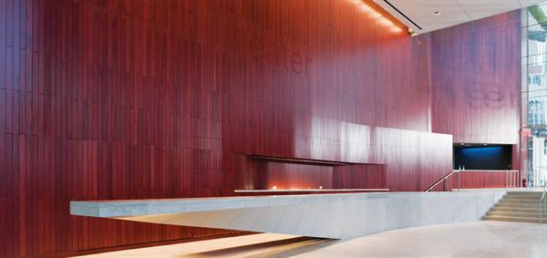 The paneling in the lobby is FSC-certified tongue-in-groove muirapiranga. The wood surface incorporates the back of the bar and the box office, covers up doors, and includes light locks where they are needed. Similarly, floors of Portuguese azul ataija limestone seem to morph into the 45-foot long cantilevered bar counter.