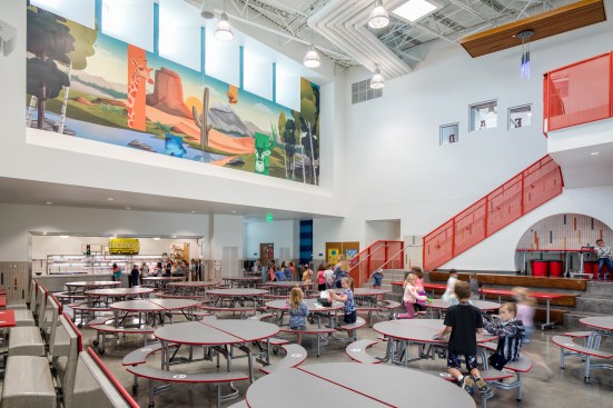 The cafeteria space is located at the heart of the building with access to the exterior. A custom graphic connects back to building themes found throughout the school. 