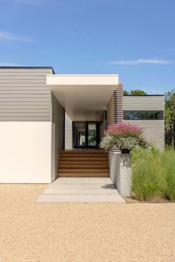 Covered breezeway entry with bleached cedar slat wall, poured-in-place concrete pavers, and ipe decking.