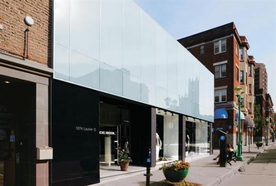 A gray glass curtainwall on the storefront reflects the neighborhood.