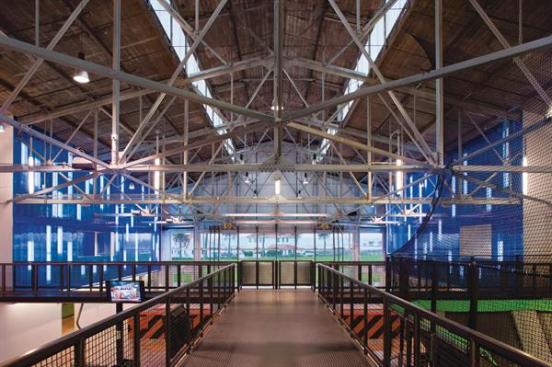 Catwalks provide access to upper-level party rooms and offices, but also afford views of all four trampoline areas: the Training Ground in the front, the green, net-enclosed dodgeball stadium and inflatable bounce-house in the middle, and the large blue field of trampolines in the rear.