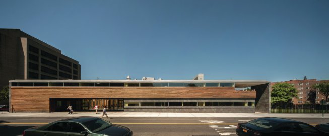 The main entry is located on the long face of the building, with its ipe cladding and slate tiles.