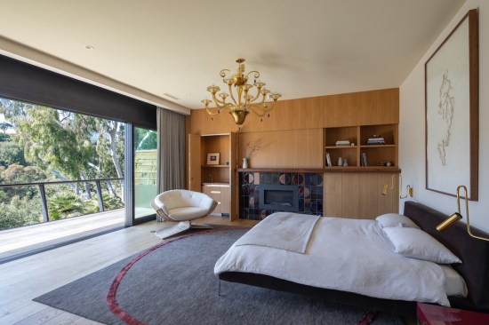 In the master bedroom, with its rift oak custom wood paneled storage and vintage furnishings, fully sliding glass doors extend the room out to the deck for sweeping views of the canyon and ocean.