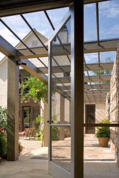 A pergola and pea-gravel terrace, often set for dining, links the main house and guesthouse.