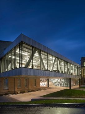 The second floor studio space hovers over the pedestrian plaza below that connects the adjacent buildings and provides outdoor gathering space.