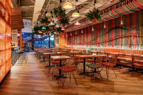 The ceiling is enveloped in hanging planters and colorful hand-crafted wicker light fixtures, custom-designed by Saladino.