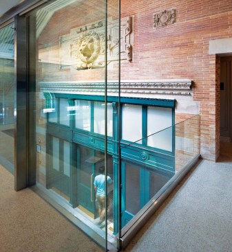 Inserted at the north end of the Schi. Family Great Hall (left) and in front of the main entry doors (opposite middle left) is a discrete volume with restrooms below and a glass-enclosed meeting room above. The base of the mezzanine is clad in large panels of limestone and detailed with bands of stainless steel. The upper-level room, which is equipped with darkening shades, can be used for breakout sessions, small luncheons, or as a bride's dressing room.