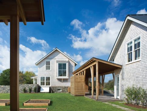 A respectful reinterpretation of New England farmhouse vernacular, this vacation compound uses a woodshedlike covered walkway to link the main house and a garage/guest apartment.