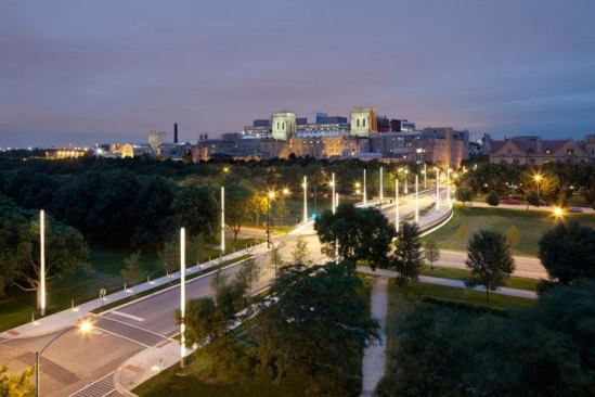 The light masts, sidewalk luminaires, and illuminated handrails create a safe and pedestrian-friendly walkway.
