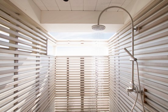 Covered outdoor shower screened with cedar slats and frosted acrylic panels for privacy on the ground level