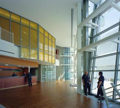 The lobby serves multiple functions: reception, waiting area, and home to impromptu gatherings of officers and neighborhood residents. The glass-enclosed space gains additional security from the canted curtain wall, which is made up of large panes of bulletproof glass.
