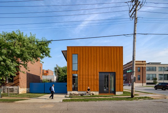 The shorter elevation matches the sizes of, and aligns with, the neighboring historic row housing, with a concrete foundation apron referencing the nearby limestone foundations. A large chunk of salvaged concrete, unearthed during site excavation, has been re-purposed as a public stoop. To accentuate the rectangular form, the roof slightly slopes behind a three-sided parapet, pitched towards the side-lot portion of the double-wide lot, with a 3-foot overhang. A bold, blue sliding door provides side-yard access to the more utilitarian, private side of the project.