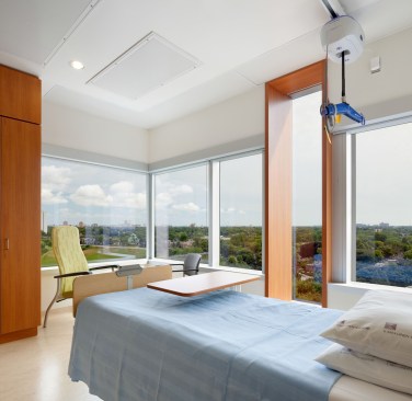 A narrow floor-to-ceiling “pop-out” window is located amongst horizontal windows in each patient room, providing dramatic views from a bed or a wheelchair.