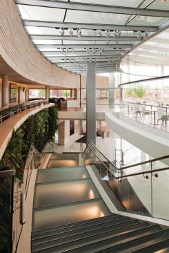 The staircase in front of the green wall leads to the upper-level balcony, on which the building's four eateries are located. At the base of the stairs is the southern ground-level entrance, which was put in as an alternative to the tunnels. "I think Fortaleza Hall is very much about encouraging the staff not to go down into tunnels, but to circulate around campus at ground level," Robinson says. "I think [the] staff have always tended to move about below ground both in the winter, when it's a necessity, but also in the summer. I think it's force of habit." Another entry, on the northern end of the hall, accommodates visitors coming from the Golden Rondelle, which has been turned into the tourism center of the complex.