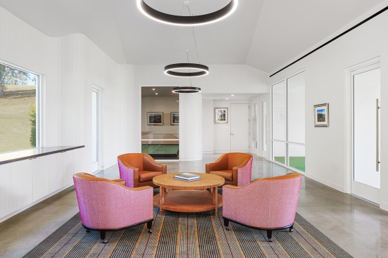 Multipurpose event space with curved walls of vertical wood planks and windows viewing into the practice studios