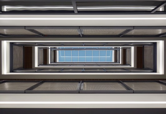 Two sectional elements work in tandem with the façade fenestration and include the central stair and a 5-story light well designed to bring natural light deep into the building and heighten the aesthetic experience.  The design features locally woven stainless steel handrails.  Pacific NW light at dusk shown. UO Tykeson Hall, OFFICE 52 Architecture, Design Architect.