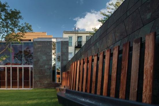 The+slate-and-glass+volume+that+houses+the+multipurpose+performance+space%2c+gallery%2c+and+library%2c+overlooks+a+sculptural+bench+in+the+landscape.