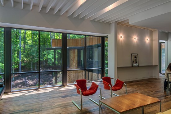 Reclaimed wood floors, recycled factory lights, and elements of the homeowners' art and furniture collection express the contrast between old and new.