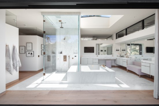The home’s expansive master bathroom features His and Hers commodes, Calcutta marble heated floors, central steam shower, spa tub, countertops and splash, wall-to-wall mirrors, and pocketing sliding doors to the deck.