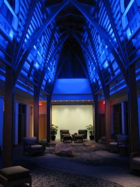 At night, the blue fluorescent lamps can be switched on, creating a dramatically changed mood and lower light level. Low-voltage mono-points with violet tinted lenses accent the garden rock features. At the end of the room, MR16 wallwashers located on both sides of the water wall create sparkle. The space is controlled by a preset dimming system.