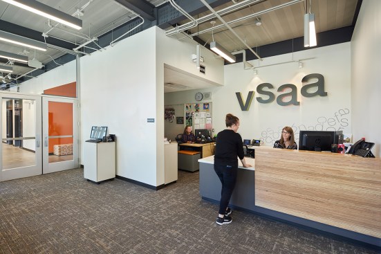Wood tones and texture compliment the calming atmosphere and engaging marquee surrounding the reception desk welcoming newcomers to the school.