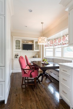Breakfast nook with beautiful dining table, banquette and pink upholstered chairs 
